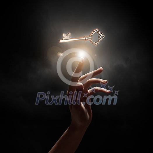 Close up of woman hand touching golden key Close up of woman hand touching golden key