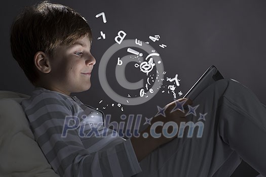 Cute little boy sitting in bed and using tablet pc Cute little boy sitting in bed and using tablet pc