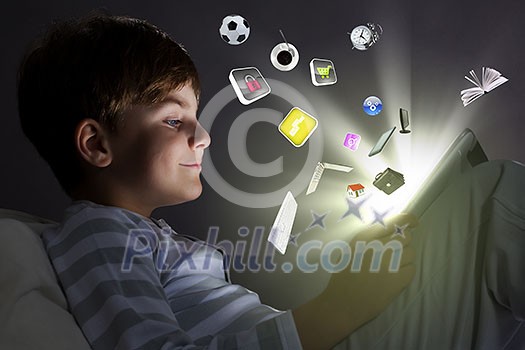 Cute little boy sitting in bed and using tablet pc Cute little boy sitting in bed and using tablet pc