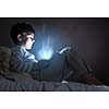 Cute boy sitting in bed and using tablet pc