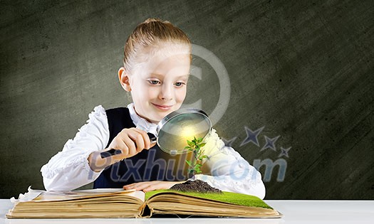 Schoolgirl examining opened book with magnifying glass Schoolgirl examining opened book with magnifying glass