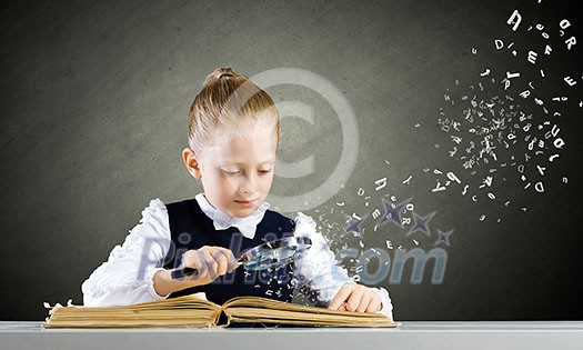 Schoolgirl examining opened book with magnifying glass Schoolgirl examining opened book with magnifying glass