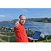 business man  engineer using laptop at solar panels plant eco energy field  in background