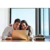 happy young relaxed  couple working on laptop computer at modern home indoor
