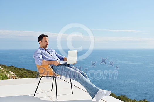 handsome young man relaxing and working on laptop computer at home balcony while looking sunset handsome young man relaxing and working on laptop computer at home balcony while looking sunset