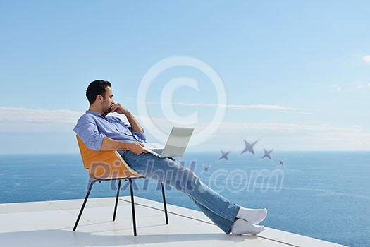 handsome young man relaxing and working on laptop computer at home balcony while looking sunset handsome young man relaxing and working on laptop computer at home balcony while looking sunset