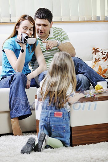 young happy family recording by video camera their child at home young happy family recording by video camera their child at home