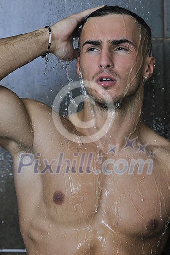 young good looking and attractive man with muscular body wet taking showe in bath with black tiles in background young good looking and attractive man with muscular body wet taking showe in bath with black tiles in background