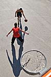 gorup of young boys who playing basketball outdoor on street with long shadows and bird view perspective