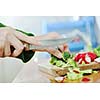 woman preparing healthy food salad with green and red vegetable and knife