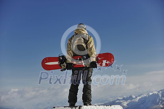 snowboarder relaxing and posing at sunny day on winter season with blue sky in background snowboarder relaxing and posing at sunny day on winter season with blue sky in background