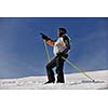 young skier relaxing, with hand pointing and  looking mountain range at beautiful sunny winter day