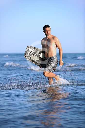 Portrait of a strong young surf man at beach on sunset in a contemplative mood with a surfboard Portrait of a strong young surf man at beach on sunset in a contemplative mood with a surfboard