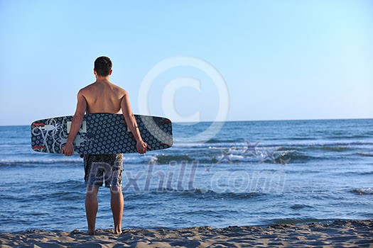 Portrait of a strong young surf man at beach on sunset in a contemplative mood with a surfboard Portrait of a strong young surf man at beach on sunset in a contemplative mood with a surfboard