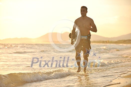Portrait of a strong young surf man at beach on sunset in a contemplative mood with a surfboard Portrait of a strong young surf man at beach on sunset in a contemplative mood with a surfboard