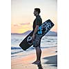 Portrait of a strong young  surf  man at beach on sunset in a contemplative mood with a surfboard