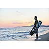 Portrait of a strong young  surf  man at beach on sunset in a contemplative mood with a surfboard