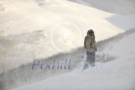 snowboarder relaxing and posing at sunny day on winter season with blue sky in background snowboarder relaxing and posing at sunny day on winter season with blue sky in background