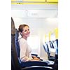 Young woman working on her laptop computer on board of an airplane during the flight