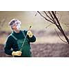 Using chemicals in the garden/orchard: gardener applying an insecticide/a fertilizer to his fruit shrubs, using a sprayer