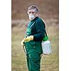 Using chemicals in the garden/orchard: gardener applying an insecticide/a fertilizer to his fruit shrubs, using a sprayer