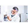 senior male researcher carrying out scientific research in a lab using a gas chromatograph (shallow DOF; color toned image)