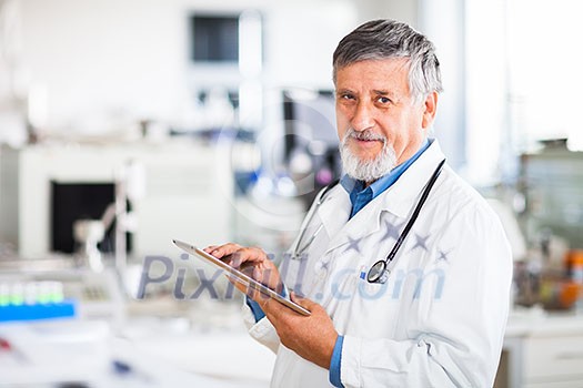 Senior doctor using his tablet computer at work (color toned image) Senior doctor using his tablet computer at work (color toned image)