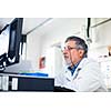 Senior researcher using a computer in the lab while working on an experiment (color toned image)