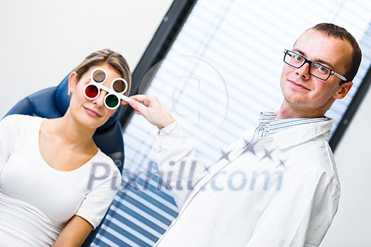 Optometry concept - pretty young woman having her eyes examined by an eye doctor/optometrist (color toned image; shallow DOF) Optometry concept - pretty young woman having her eyes examined by an eye doctor/optometrist (color toned image; shallow DOF)