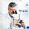 senior male researcher carrying out scientific research in a lab using a microscope (shallow DOF; color toned image)