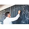 Senior chemistry professor writing on the board while having a chalk and blackboard lecture (shallow DOF; color toned image)