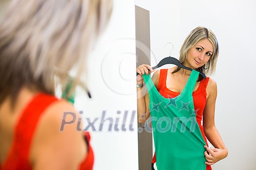 Young woman shopping in a fashion store - Trying on the garments she likes (color toned image; shallow DOF) Young woman shopping in a fashion store - Trying on the garments she likes (color toned image; shallow DOF)