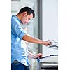 Handsome  young man using a copy machine (shallow DOF; color toned image)