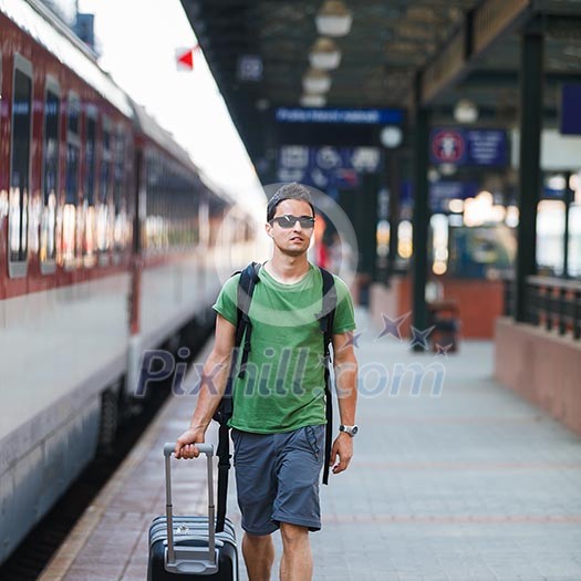 Just arrived: handsome young man walking along a platform at a modern train station Just arrived: handsome young man walking along a platform at a modern train station