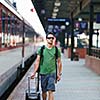 Just arrived: handsome young man walking along a platform at a modern train station