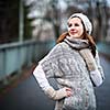 Autumn/winter portrait: young woman dressed in a warm woolen cardigan posing outside in a city park