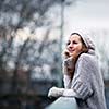 Autumn/winter portrait: young woman dressed in a warm woolen cardigan posing outside in a city park