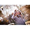 Autumn/winter portrait: young woman dressed in a warm woolen cardigan posing outside in a city park