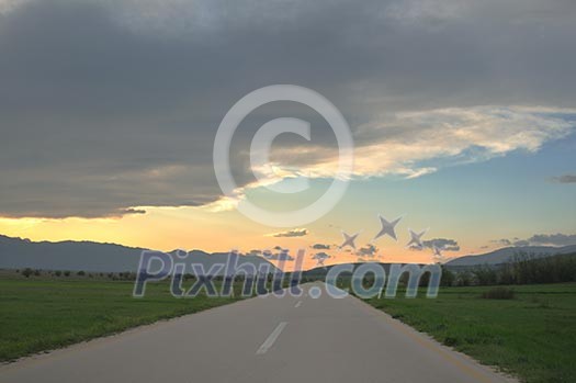 landscape in nature and countryroad adventure with beautiful sunset and dramatic clouds and sky