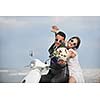 wedding sce of bride and groom just married couple on the beach ride white scooter and have fun