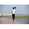 Running in city park. Woman runner outside jogging at morning with Dubai urban scene in background