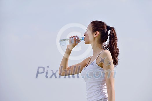Young beautiful woman drinking water after fitness exercise and jogging outdoors Young beautiful woman drinking water after fitness exercise and jogging outdoors