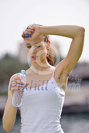 Young beautiful woman drinking water after fitness exercise and jogging outdoors Young beautiful woman drinking water after fitness exercise and jogging outdoors