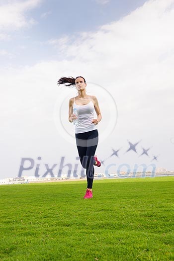 Running in city park. Woman runner outside jogging at morning with Dubai urban scene in background Running in city park. Woman runner outside jogging at morning with Dubai urban scene in background