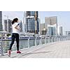 Running in city park. Woman runner outside jogging at morning with Dubai urban scene in background