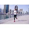 Running in city park. Woman runner outside jogging at morning with Dubai urban scene in background