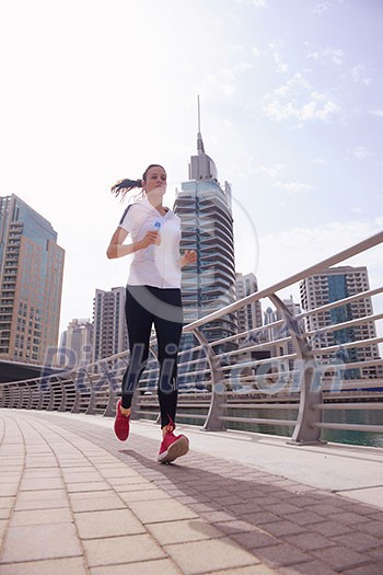 Running in city park. Woman runner outside jogging at morning with Dubai urban scene in background Running in city park. Woman runner outside jogging at morning with Dubai urban scene in background