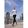 Running in city park. Woman runner outside jogging at morning with Dubai urban scene in background