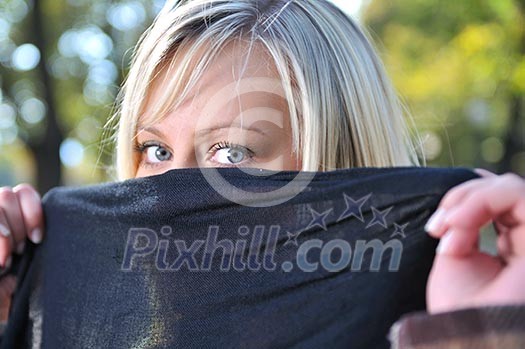 Young woman hiding face behind scarf Young woman hiding face behind scarf
