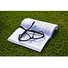 Glasses on a book outside with grass inbbacground, education relax and study concept